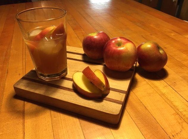 A refreshing cocktail made of bourbon and Downeast Cider House cider accompanied by sliced apples.