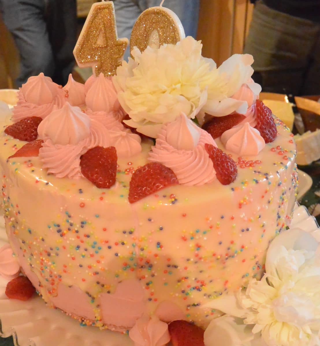 beautiful birthday cake iced with sprinkles and topped with strawberries and cream