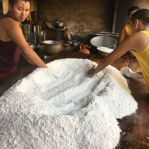 Two boys working together on a large pile of flour