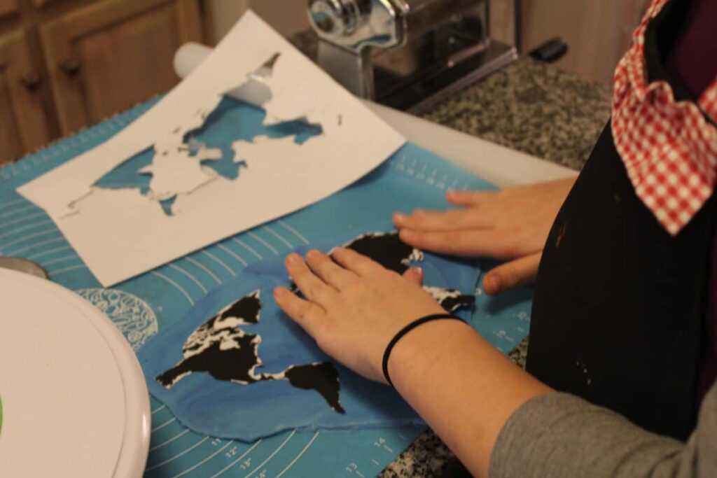 Hands placing world map design on cake