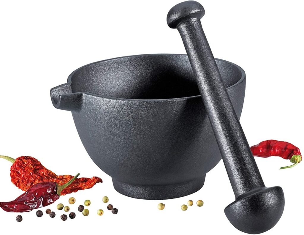Black cast iron mortar and pestle with spices around it