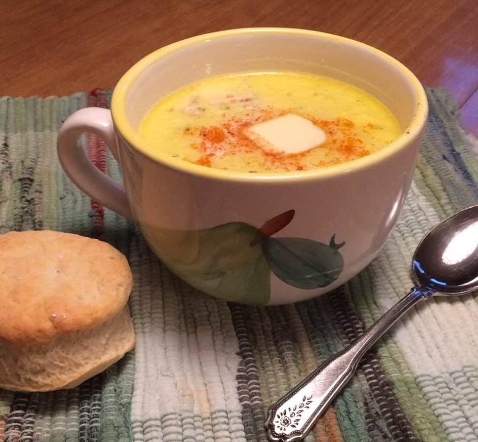 Warm cup of seafood chowder served with a biscuit and spoon