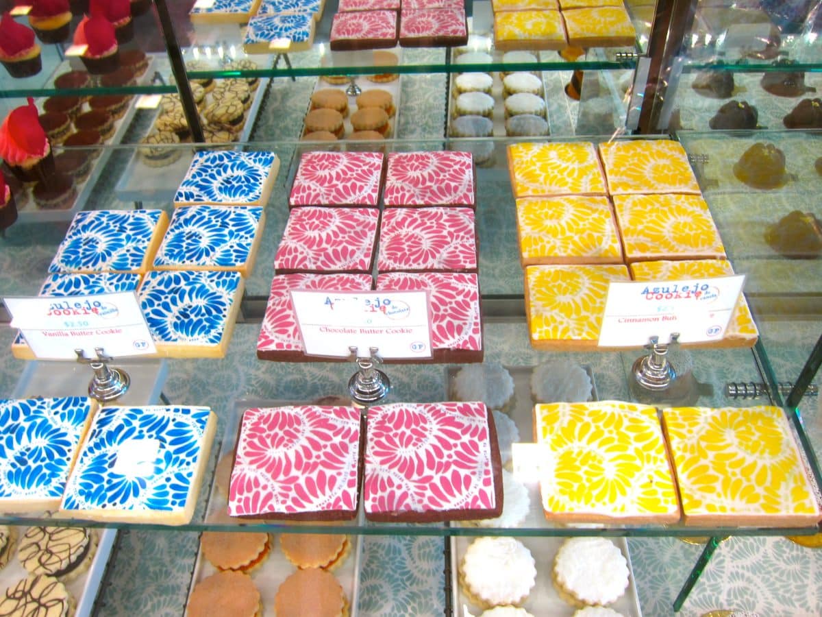 Display of colorful Mexican tile cookies in blue, pink, and yellow patterns.