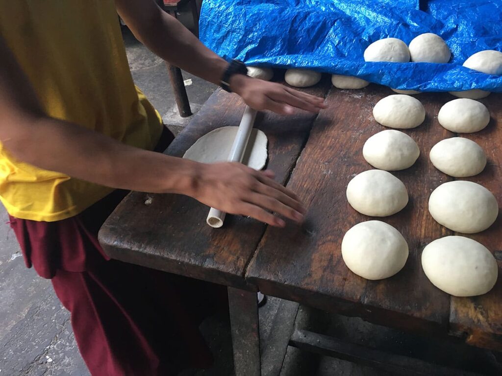 Young boy rolling dough on wooden surface