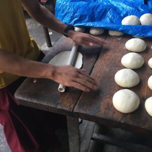 Young boy rolling dough on wooden surface