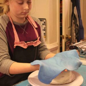 Young girl working with blue fondant on a kitchen table.