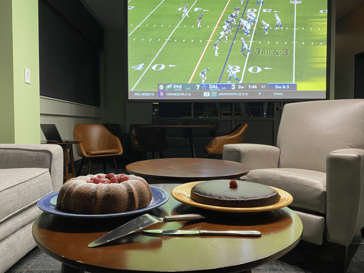 Two cakes in front of large screen football