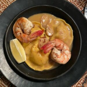 Close-up of lobster ravioli served with jumbo shrimp in a creamy sauce.