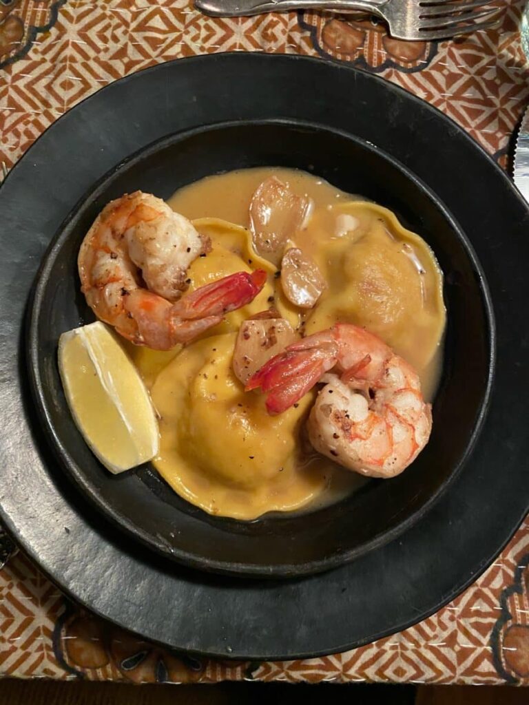 Close-up of lobster ravioli served with jumbo shrimp in a creamy sauce.