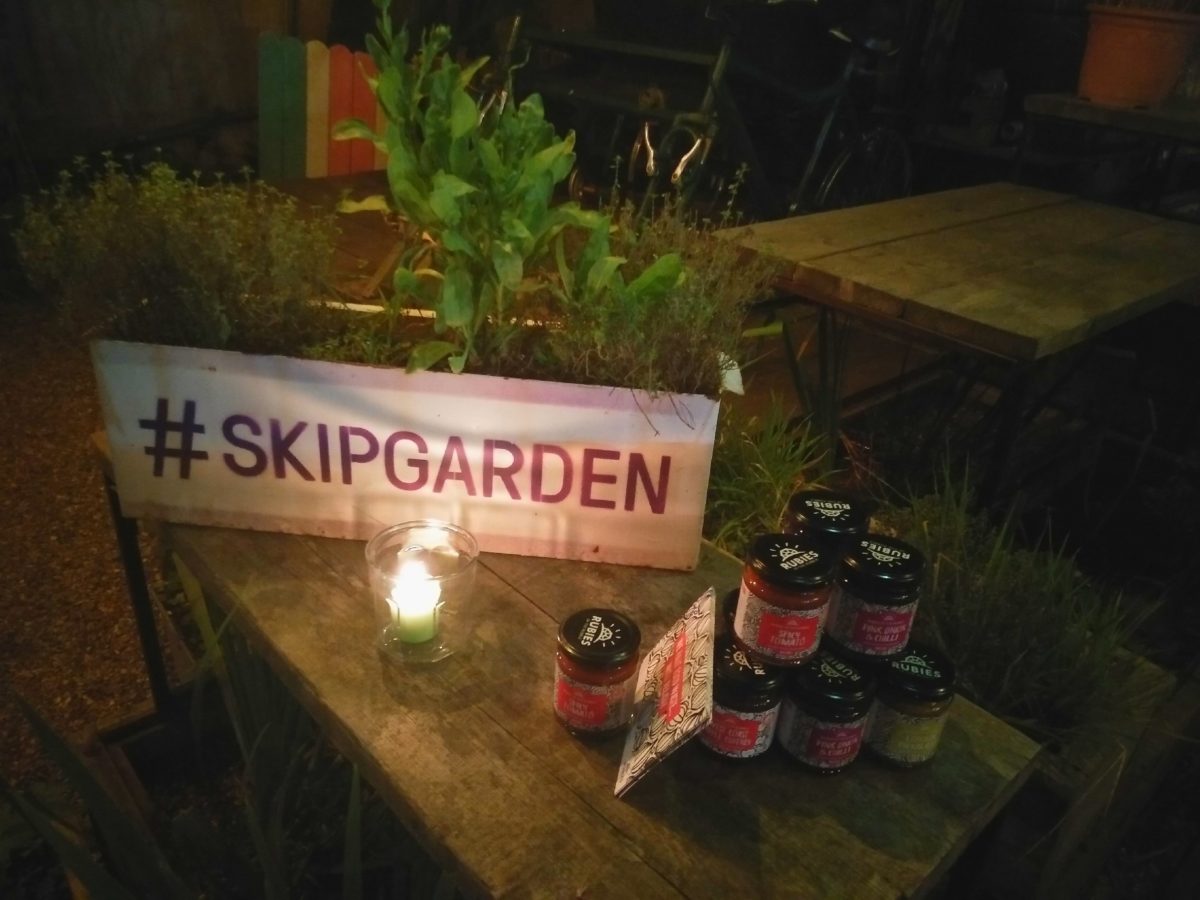 #SKIPGARDEN sign beside a candle and stack of jams