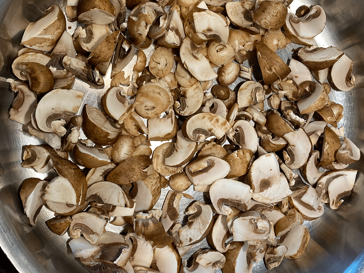 Slice cremini mushrooms in pan