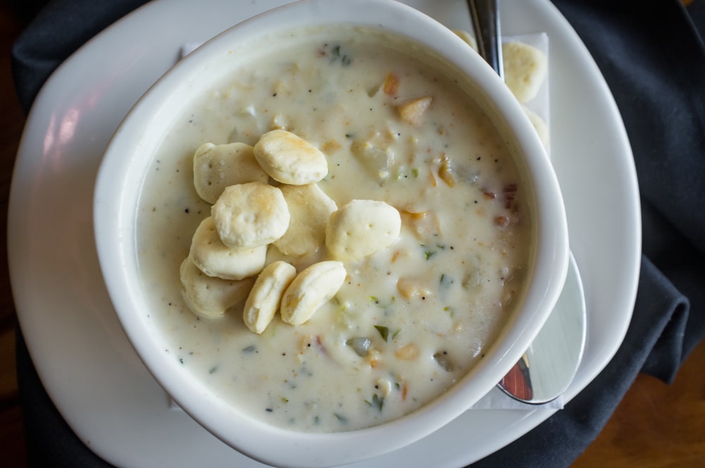 Bowl of New England Clam Chowder with oyster crackers on top.