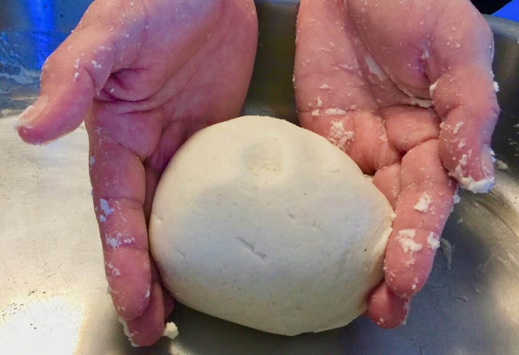 Hands holding a formed ball of masa dough
