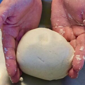 Hands holding a formed ball of masa dough