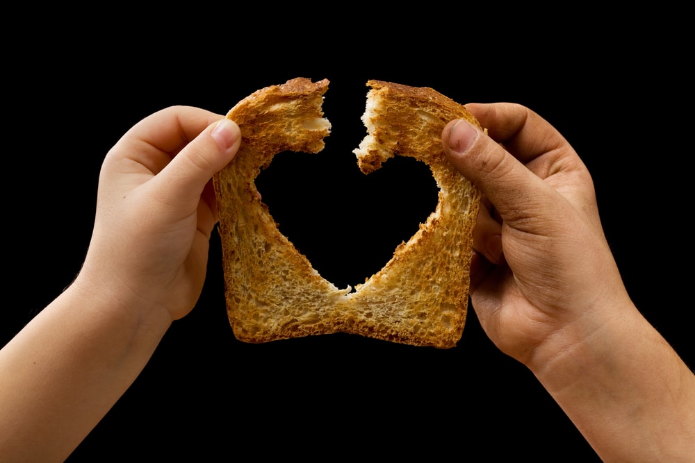 Sharing food with love - kids' hands breaking a slice of bread