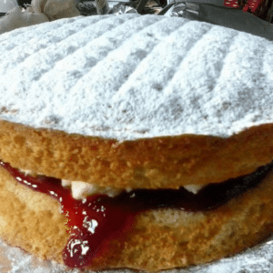 Layered Victoria sponge cake with jam filling and powdered sugar top.